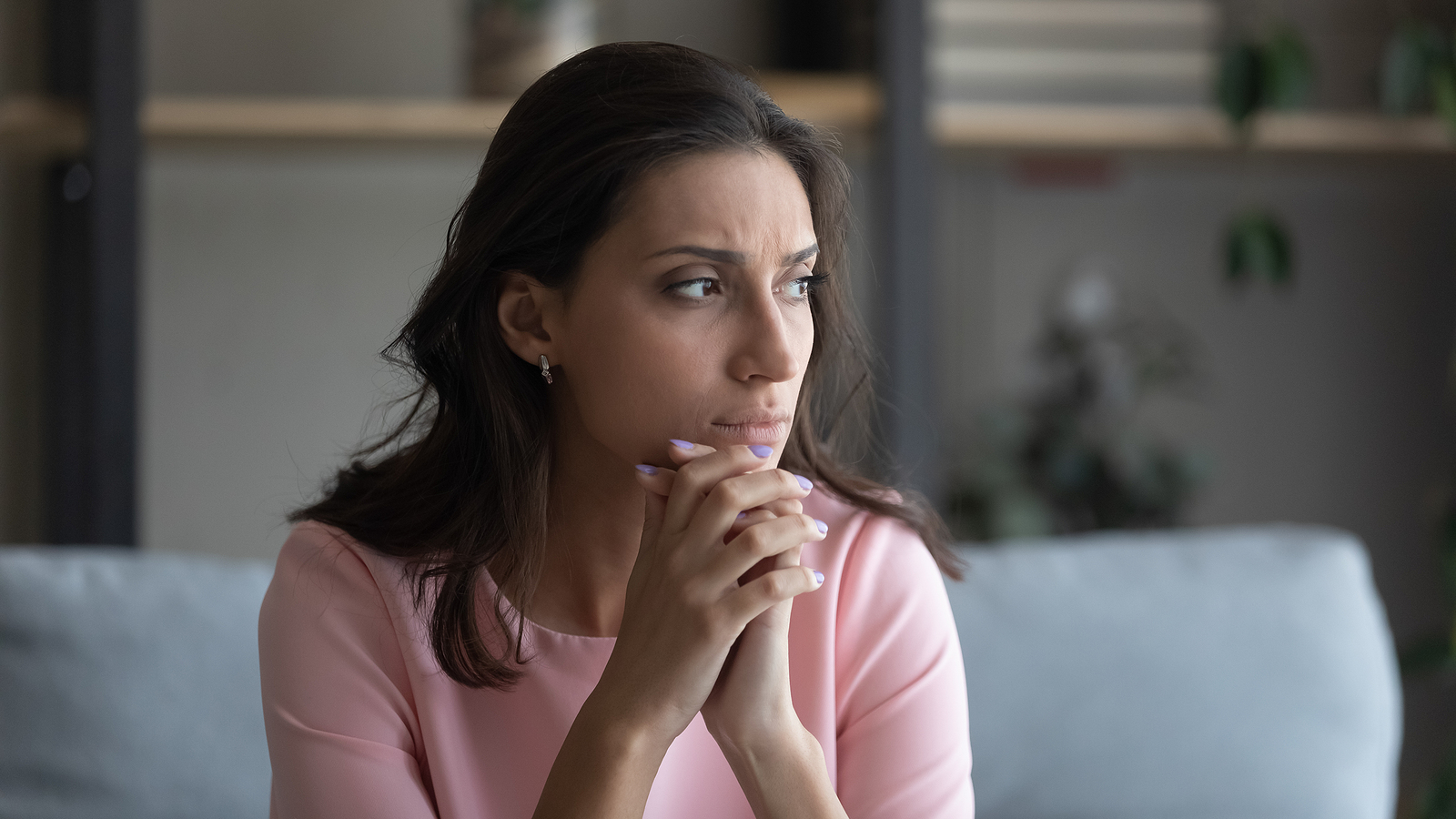Woman sitting thoughtfully on a couch, reflecting on her mental and emotional health