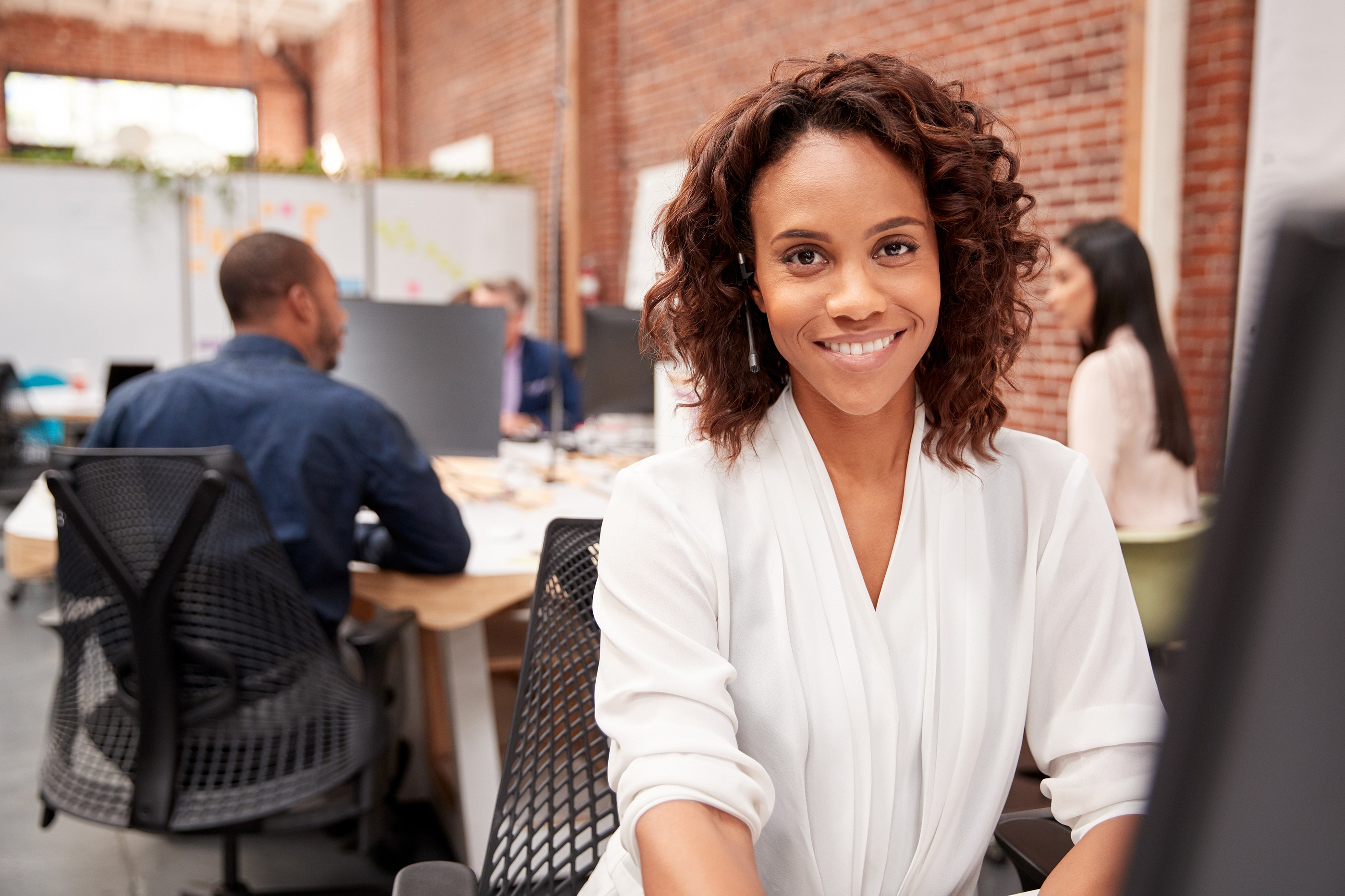 A smiling Lyric customer service representative wearing a headset in a modern office