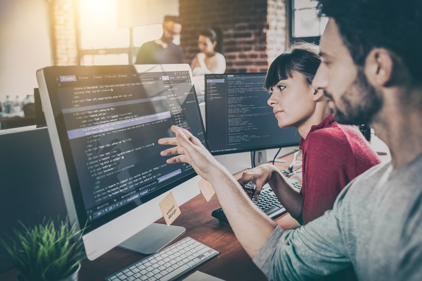 Two Lyric developers reviewing code together on monitors while building on the care operating system