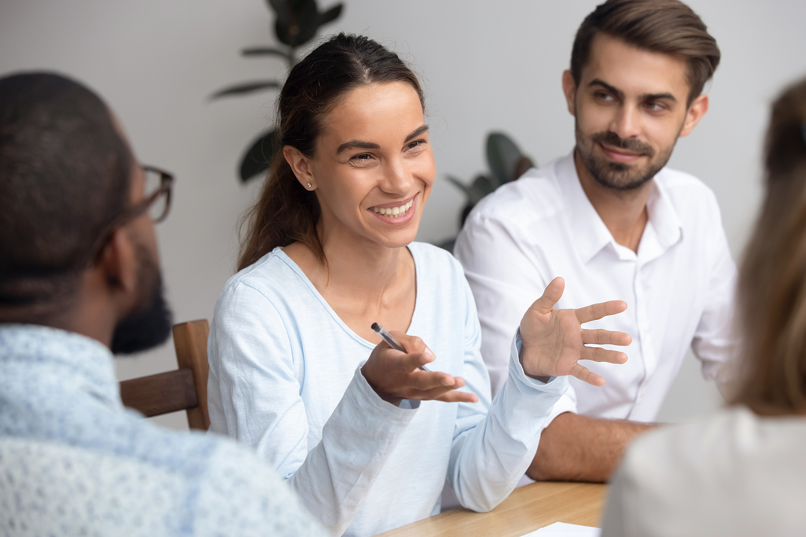 A benefits leader smiling and gesturing while discussing a partnership with colleagues around a conference table